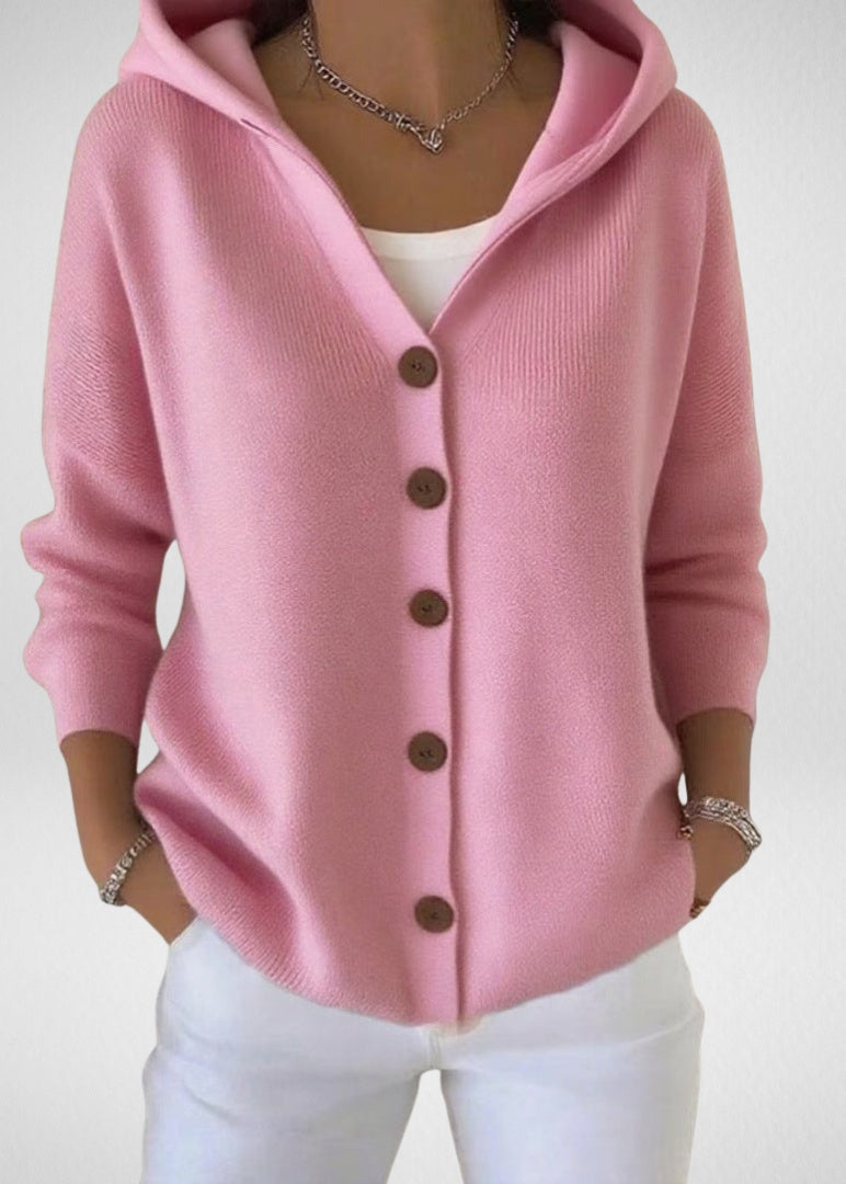 Roze gebreid capuchonvest met knoopsluiting, gedragen door vrouw met witte broek | Boutique Moda