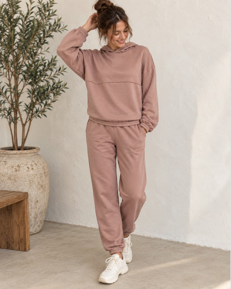 Vrouw in een oudroze joggingpak met hoodie