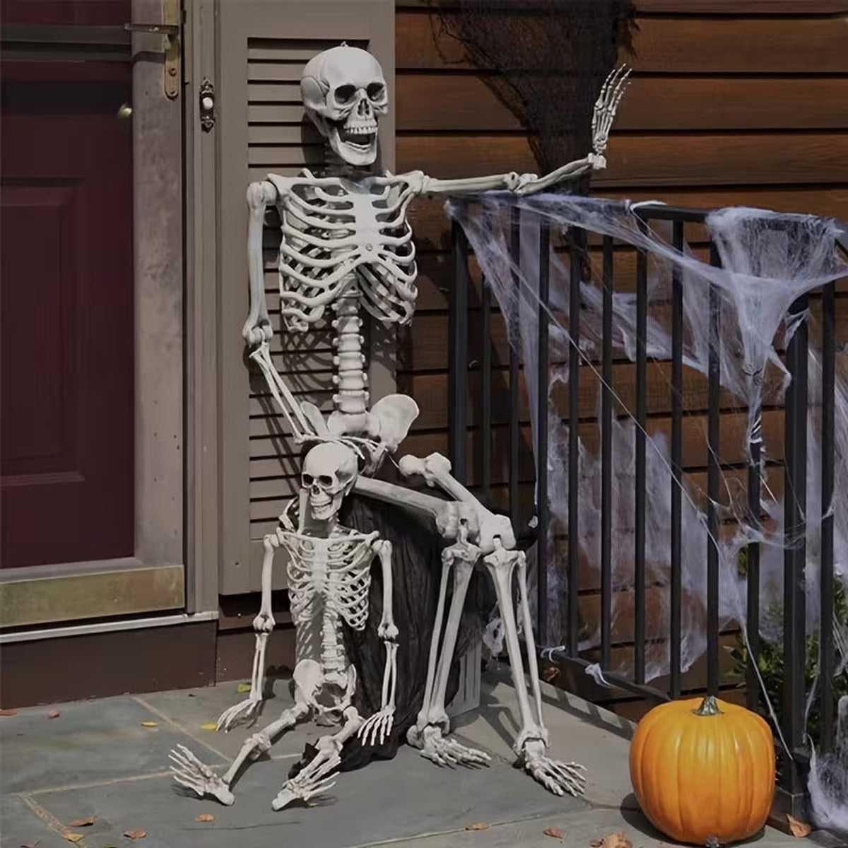 Skelet op de veranda voor Halloween, met een kleiner skelet op schoot