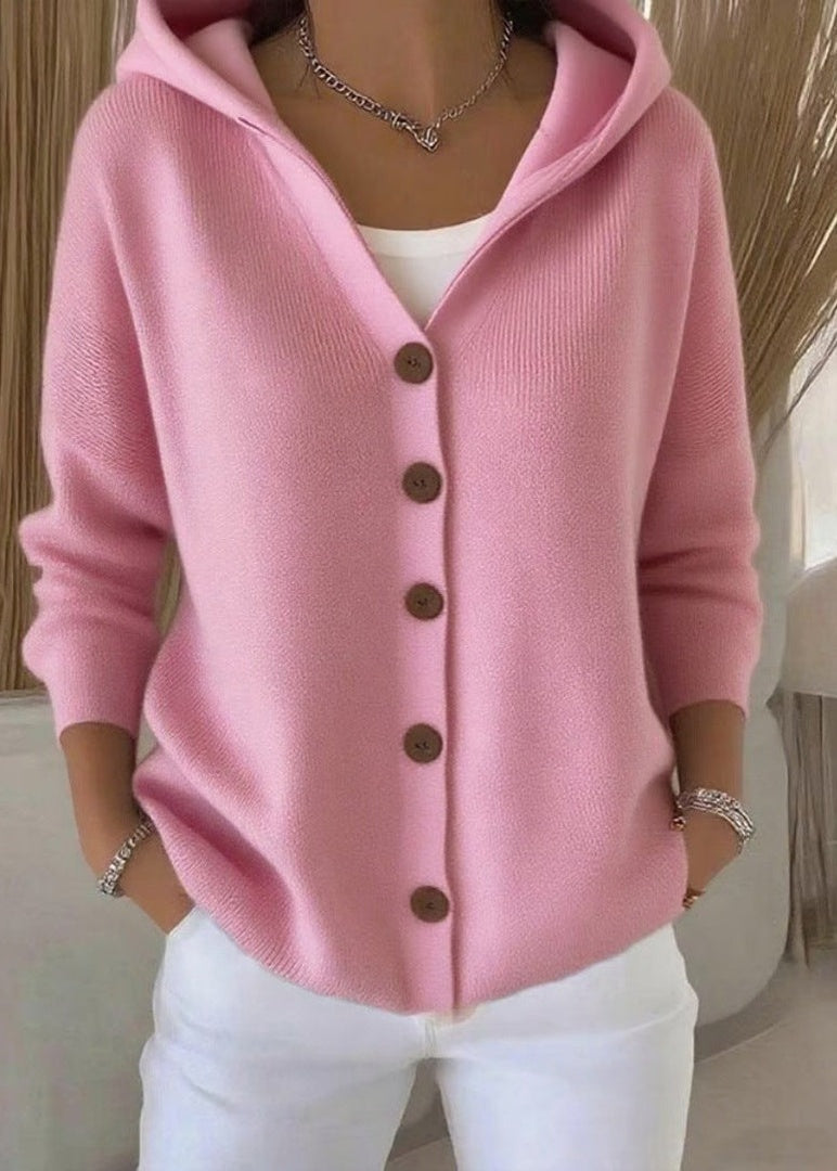 Roze gebreid capuchonvest met knoopsluiting, gedragen door een vrouw met witte broek | Boutique Moda