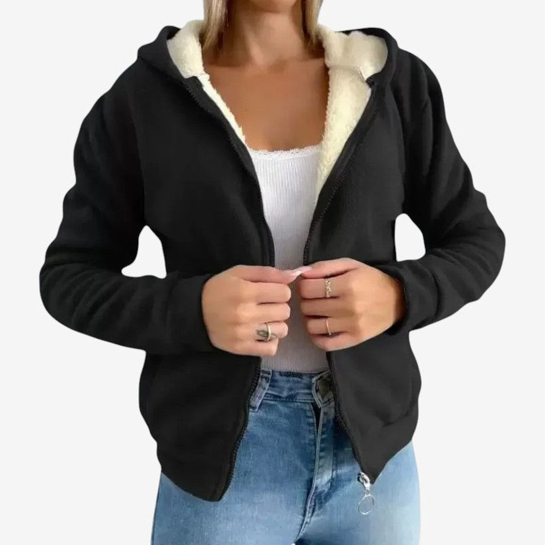 Vrouw draagt zwart fleecevest met crèmekleurige teddyvoering over een wit topje en jeans | Boutique Moda