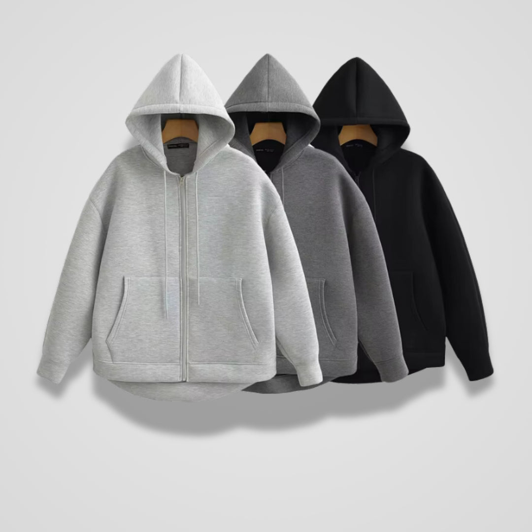 Drie oversized vesten in lichtgrijs, donkergrijs en zwart naast elkaar aan kleerhangers | Boutique Moda
