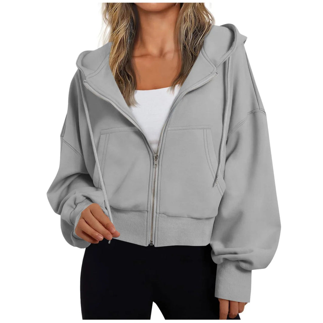 Vrouw in een grijs vest met grote capuchon en koorden, half open over een wit topje | Boutique Moda