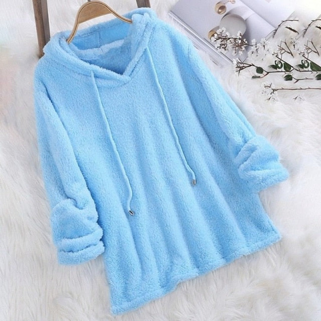 Lichtblauwe hoodie van teddyfleece aan een kleerhanger op een wit, pluizig kleed | Boutique Moda