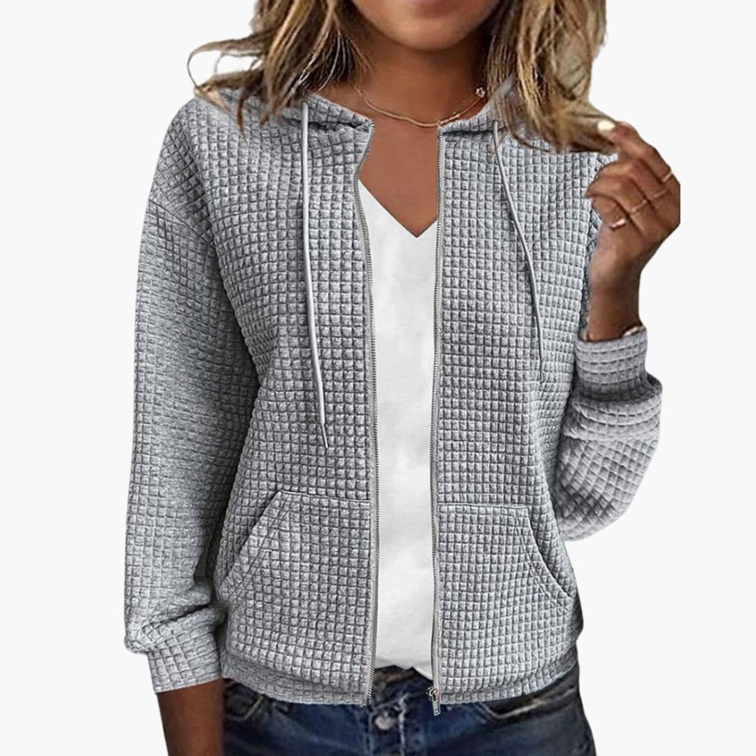 Vrouw in een grijs wafelvest met koorden aan de capuchon en twee opgestikte zakken | Boutique Moda