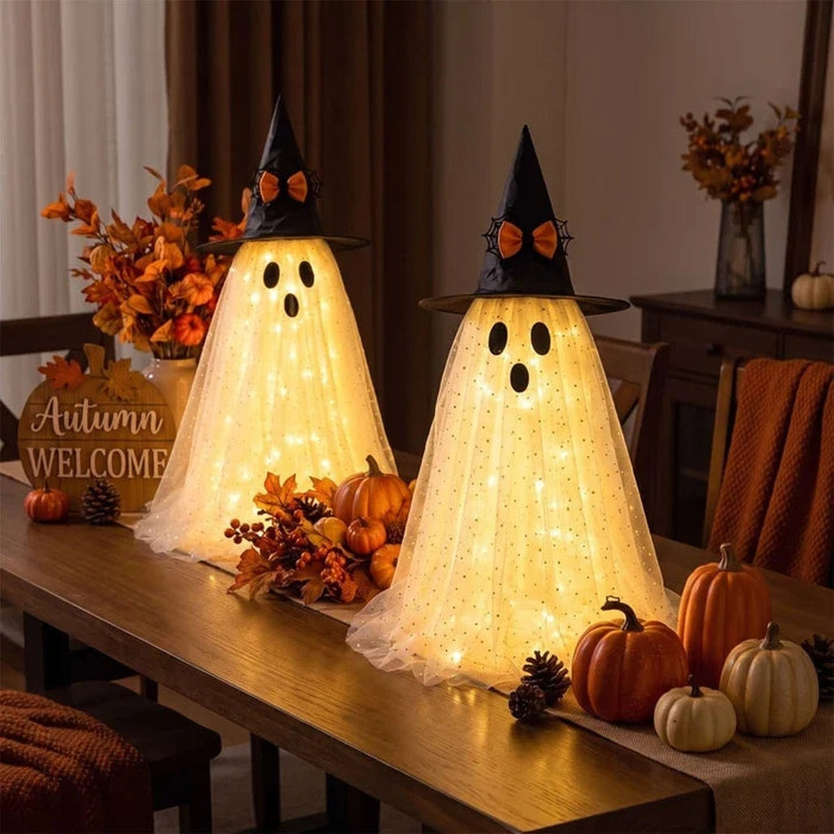 Twee lichtgevende spookjes met heksenhoed op een houten tafel