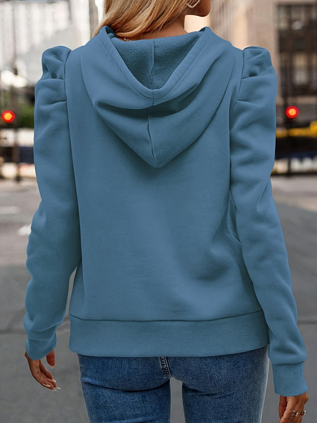 Achteraanzicht van de grijsblauwe hoodie met capuchon en pofmouwen op straat | Boutique Moda