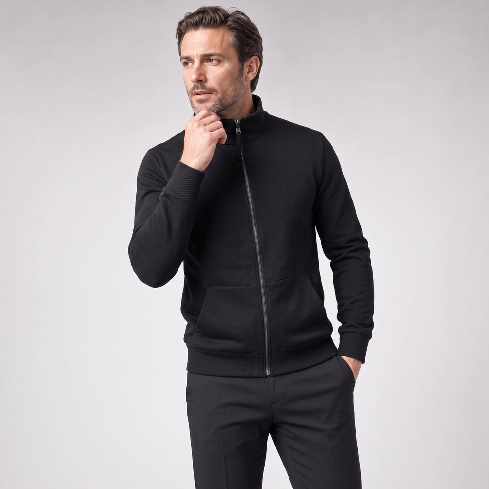 Man in een zwart sweatvest met een zwarte broek, met een hand bij zijn kin | Boutique Moda