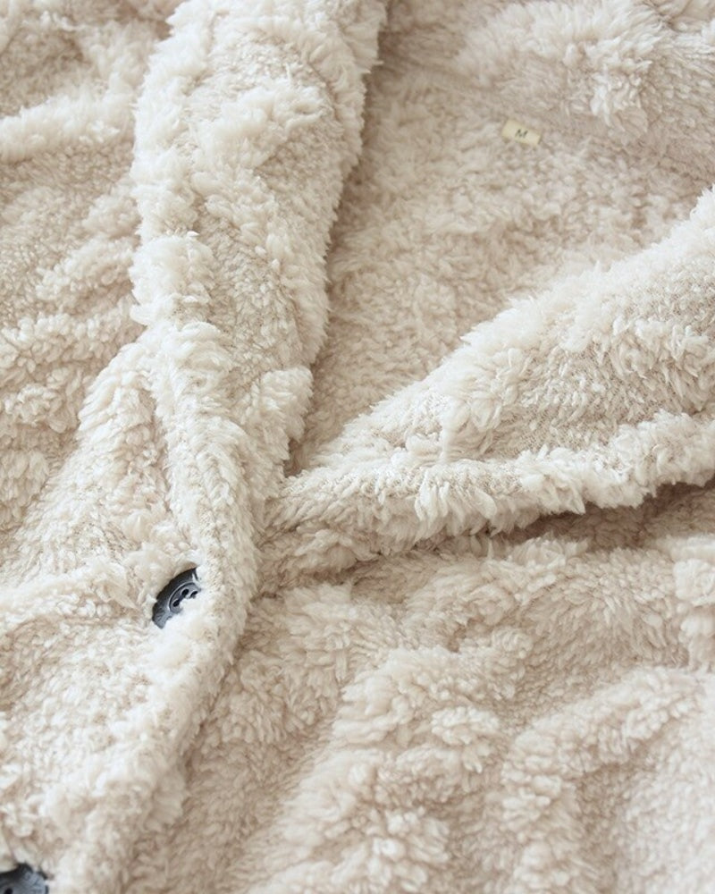 Sjaalkraag en knoopsluiting van de crèmekleurige fleece pyjama, close-up