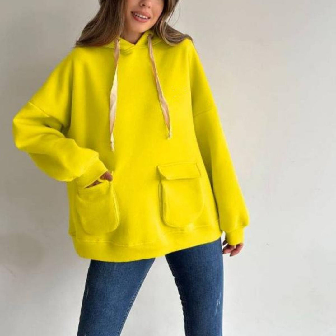 Vrouw in een neongele oversized hoodie met een jeans, hand in de klepzak | Boutique Moda