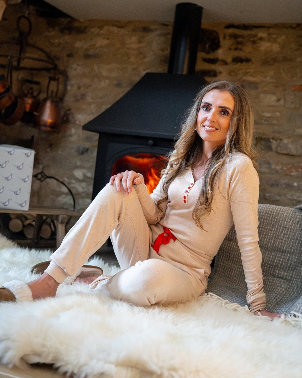 Havermoutkleurige pyjamabroek met gekleurde spikkels en boorden, zittend bij de open haard gedragen