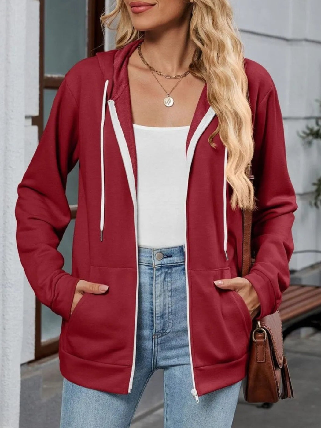 Vrouw draagt open rood capuchonvest met witte bies langs de rits en steekzakken | Boutique Moda