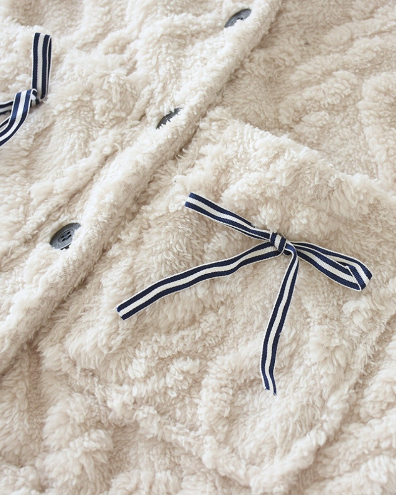 Opgestikte zak met gestreepte strik op de crèmekleurige fleece pyjamatop, close-up