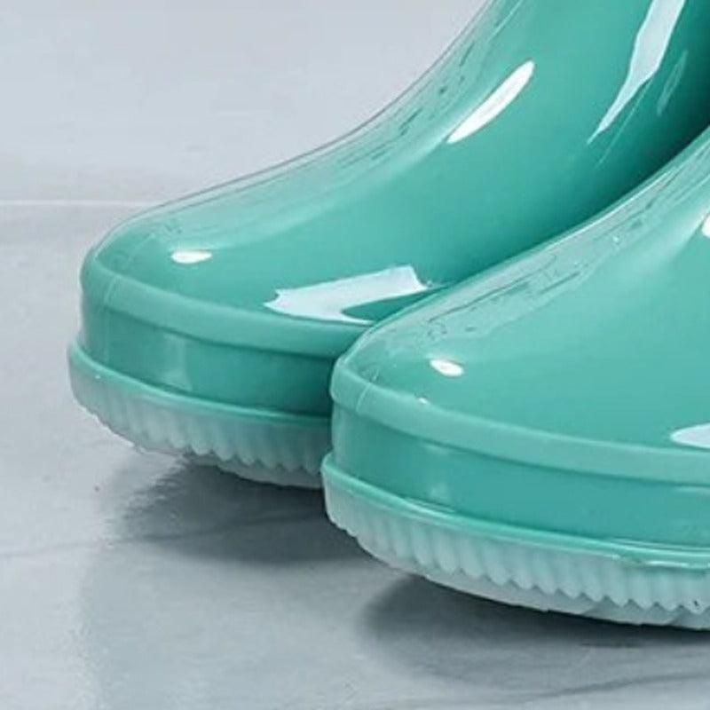 Glanzende regenlaarzen met geometrisch reliëf in turquoise, close-up van de zool