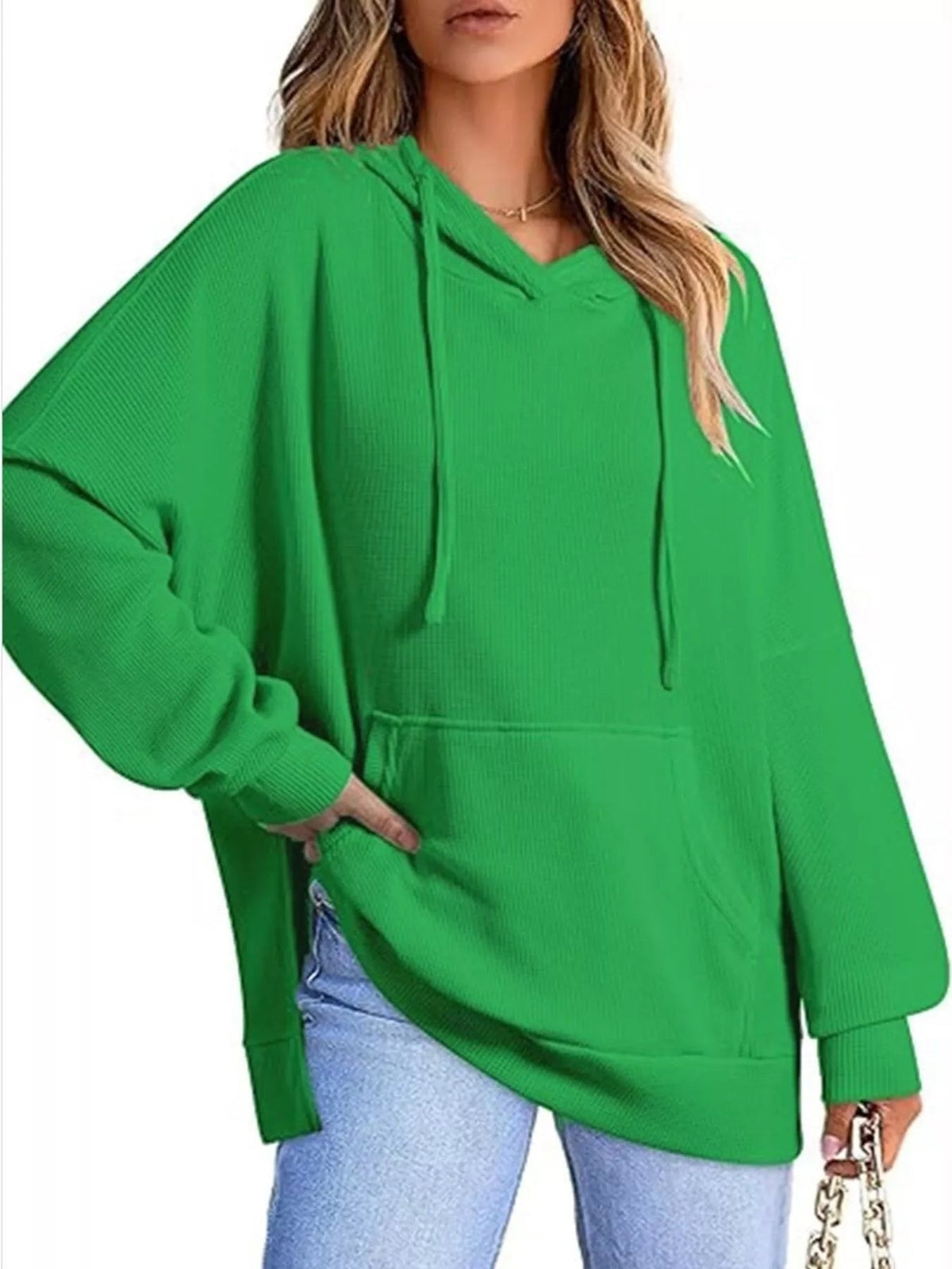 Vrouw in groene oversized capuchontrui met wafelstructuur en wijde mouwen | Boutique Moda