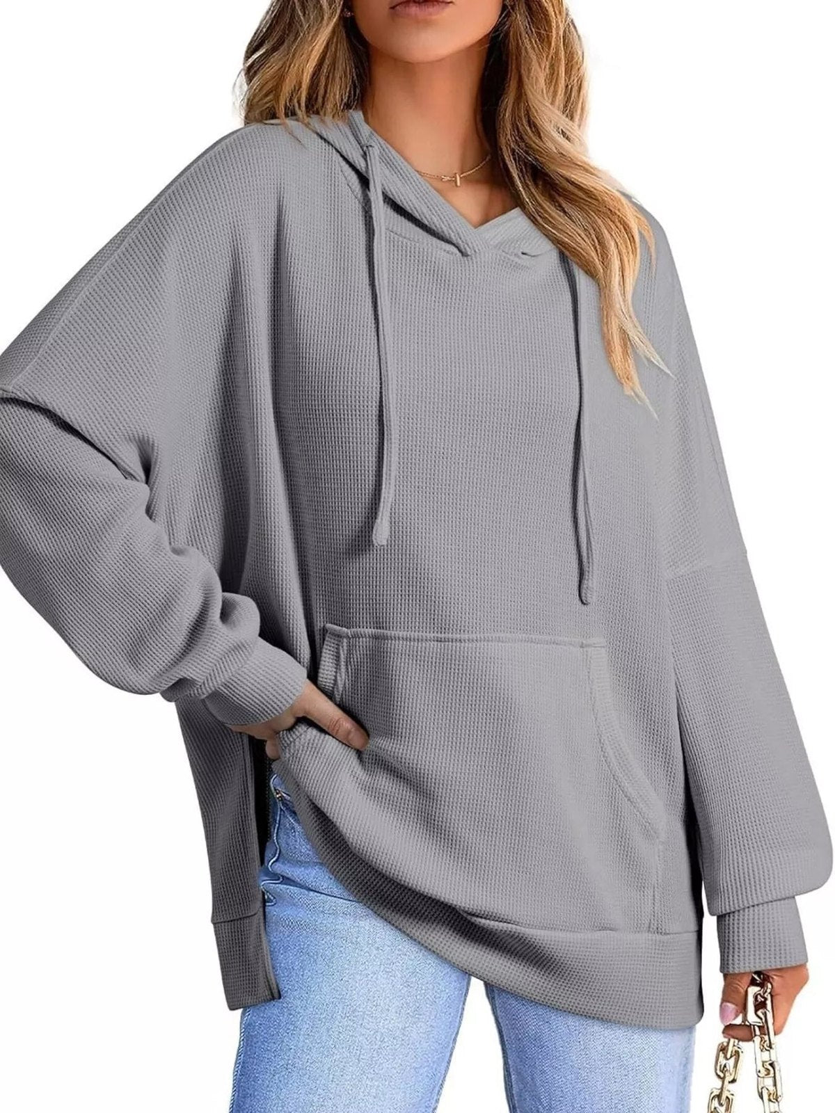 Vrouw in grijze oversized capuchontrui met kangoeroezak en lichte jeans | Boutique Moda