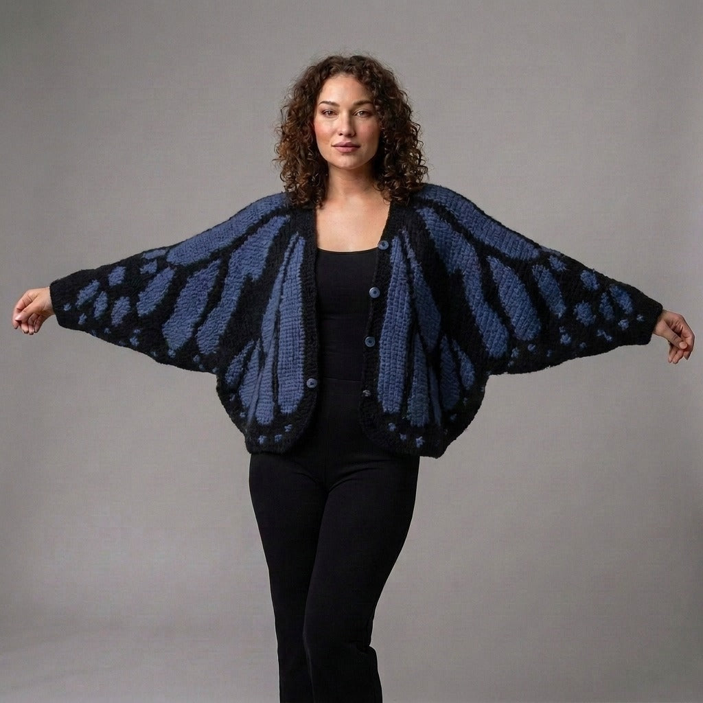 Oversized vest met vlinderpatroon in blauw, gedragen met gespreide armen, zodat je de vleugels ziet