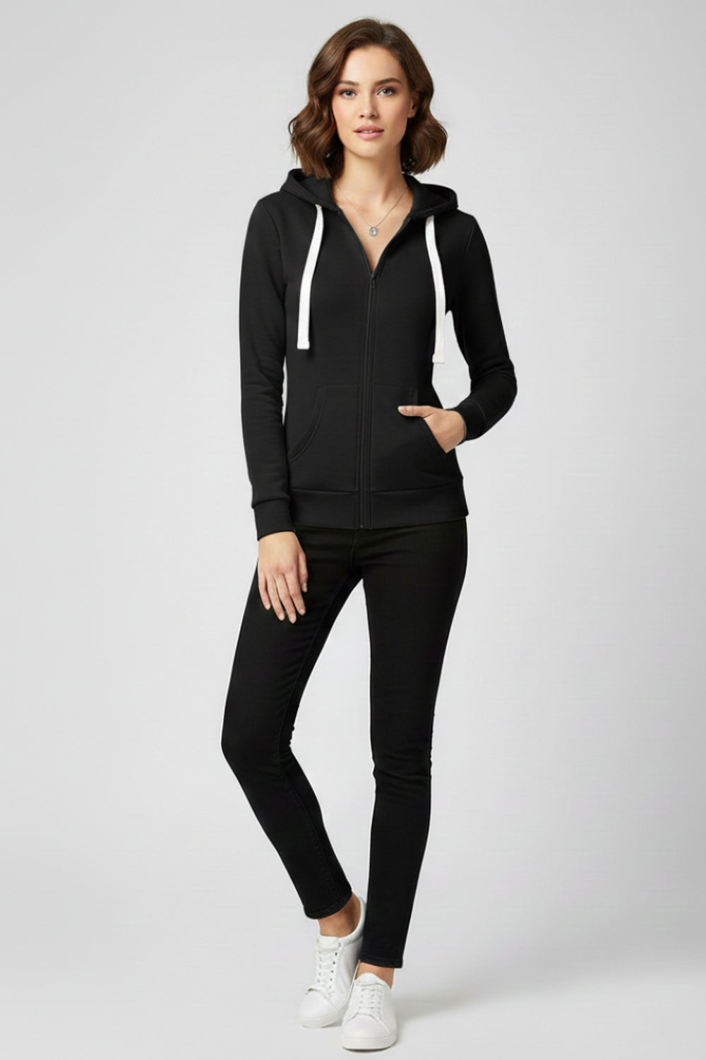 Vrouw in een zwart vest met witte koorden, een zwarte broek en witte sneakers | Boutique Moda