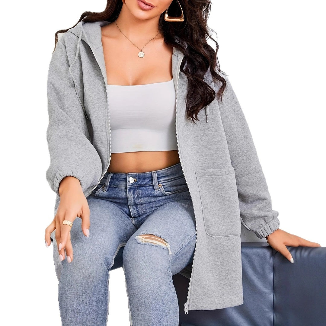 Vrouw zit in open lang grijs vest over een wit cropped topje en een jeans | Boutique Moda