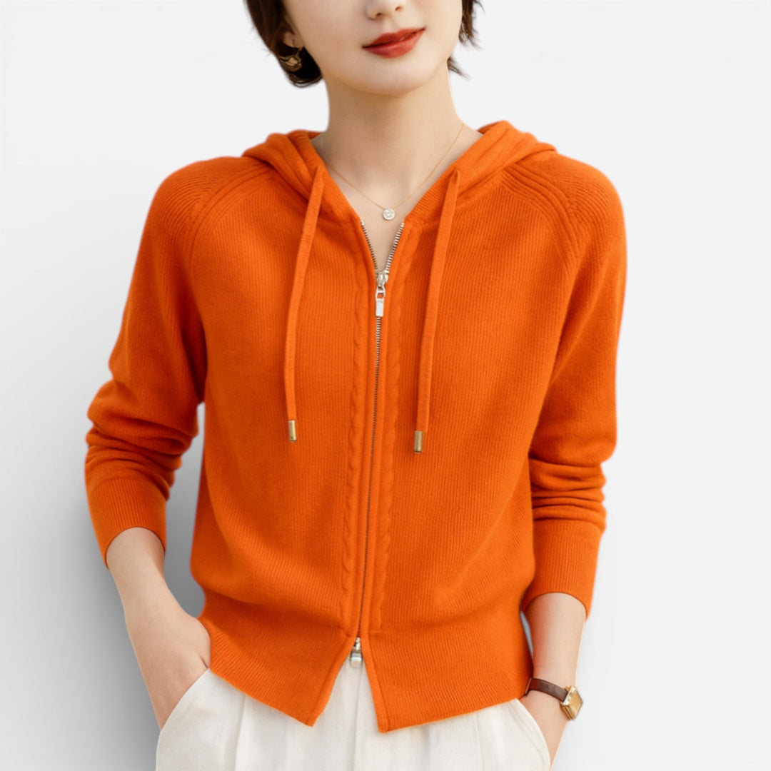 Vrouw draagt een oranje gebreid vest met dubbele rits, handen in de broekzakken | Boutique Moda