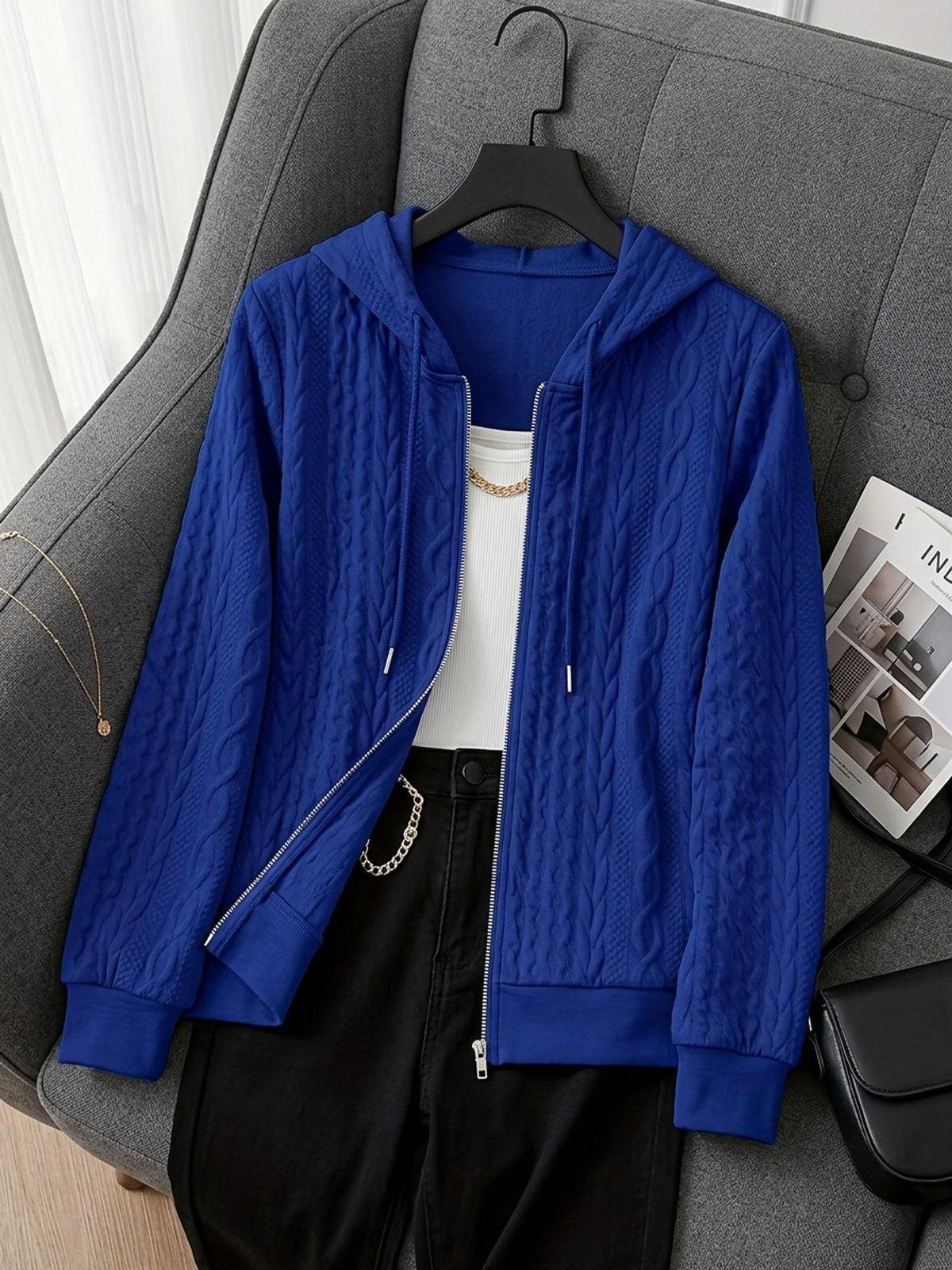 Koningsblauwe hoodie met rits aan een hanger over een fauteuil, met wit topje | Boutique Moda