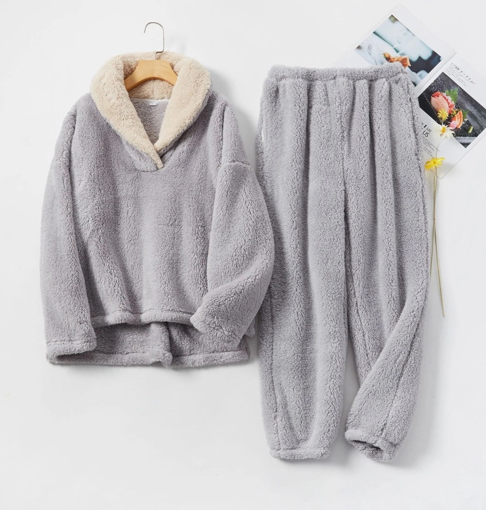 Fleecepyjama in lichtgrijs met crèmekleurige sjaalkraag, trui aan een kledinghanger, broek ernaast