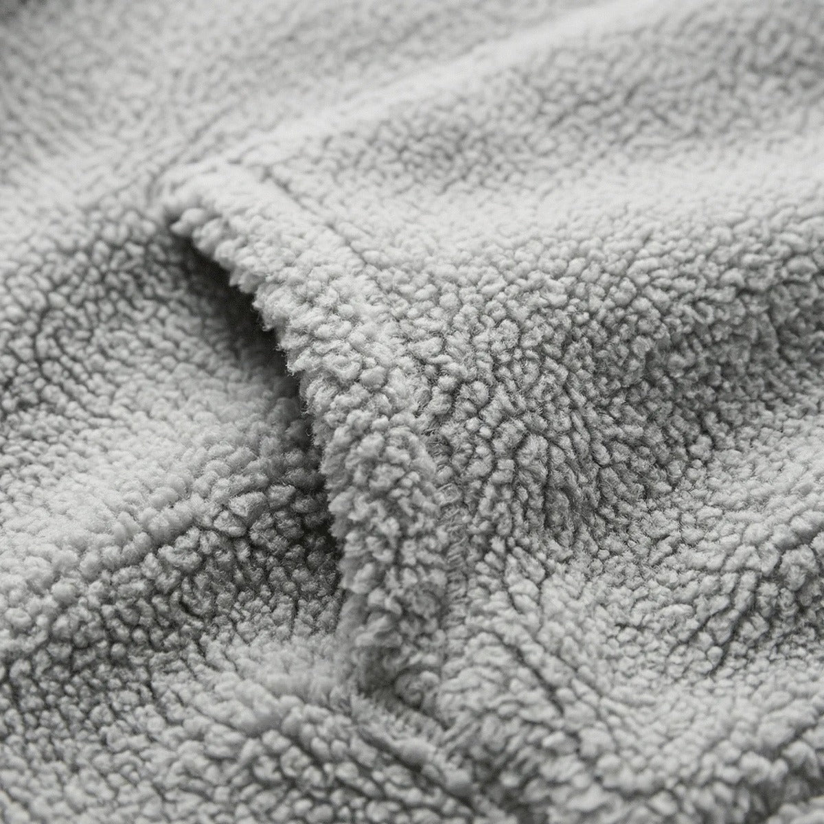 Close-up van de grijze teddyfleece met krulletjes en de kangoeroezak