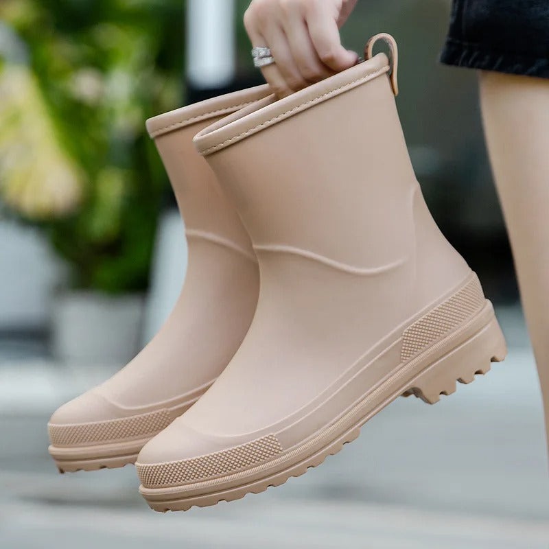 Korte rubberen laarzen, mat in beige, in de hand gehouden