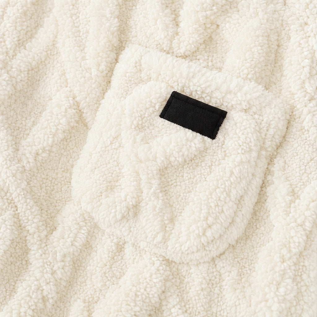 Opgestikte borstzak met een zwart labeltje op de crèmekleurige hoodie, close-up