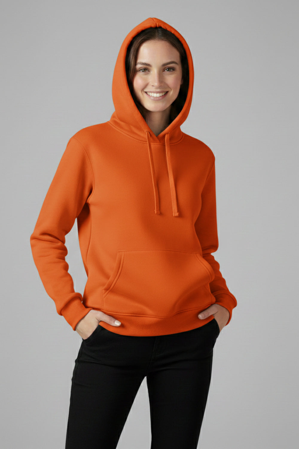 Vrouw in een oranje basic hoodie, handen in de broekzakken | Boutique Moda