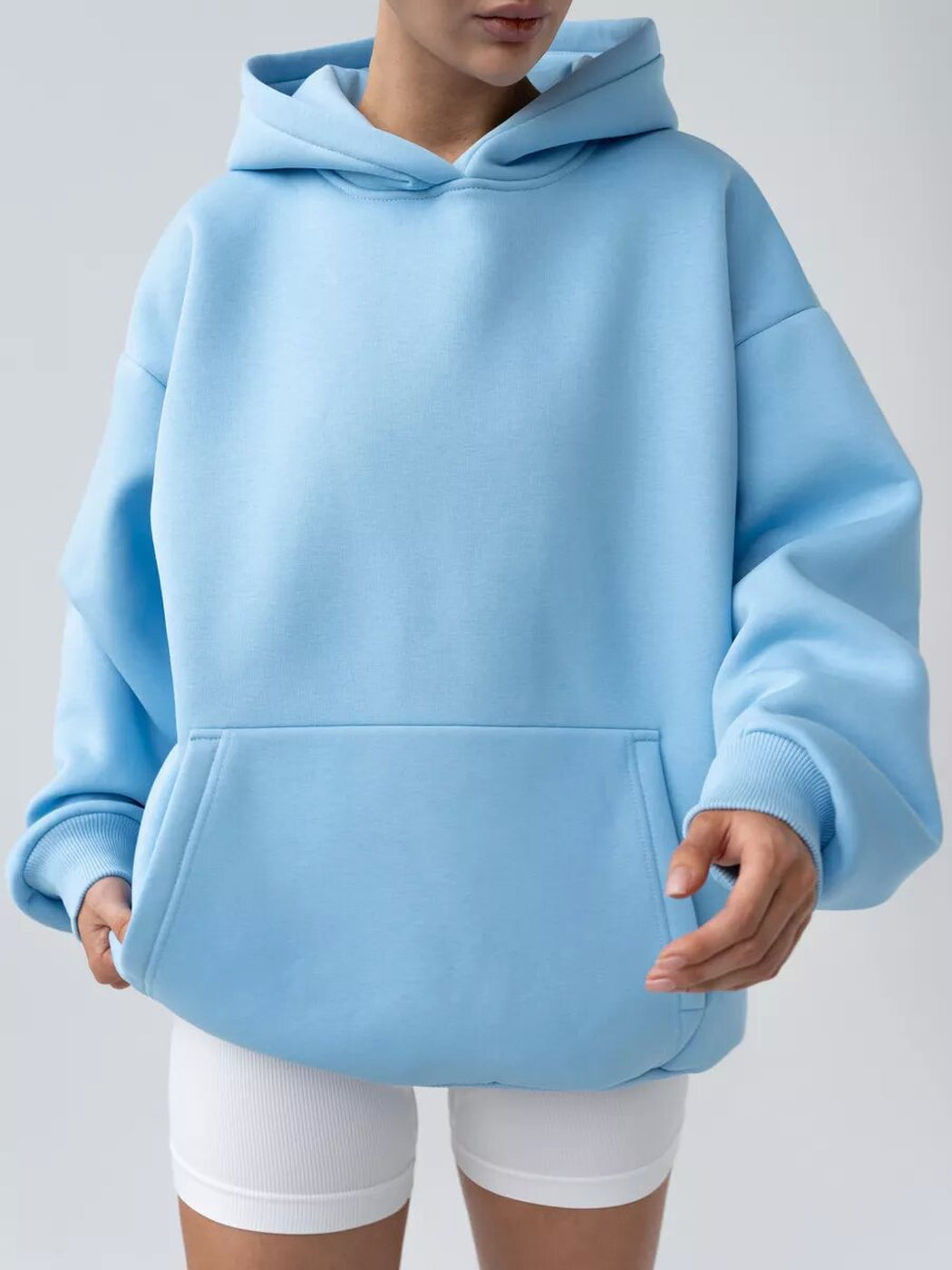 Vrouw in een hemelsblauwe hoodie met kangoeroezak en witte shorts | Boutique Moda