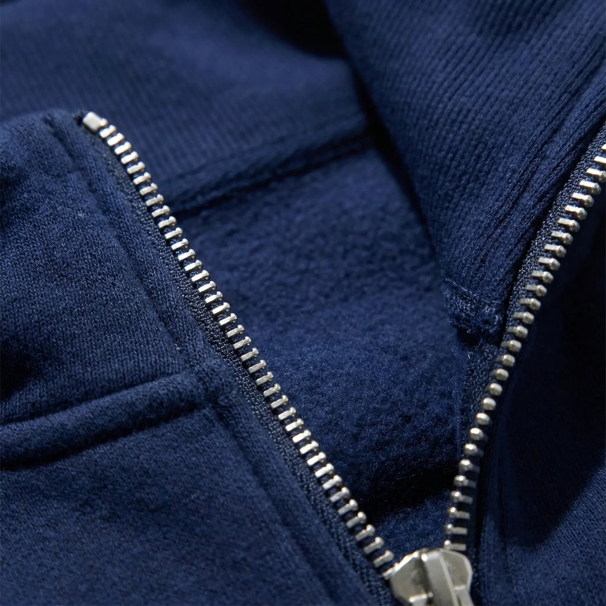 Close-up van de zilverkleurige halve rits en de geborstelde binnenkant in marineblauw