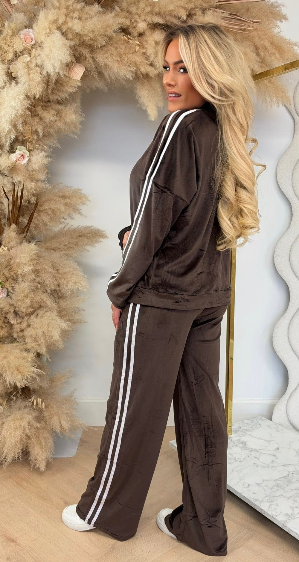 Velours joggingpak in donkerbruin met witte zijstrepen, vest met rits en rechte broek, zijaanzicht