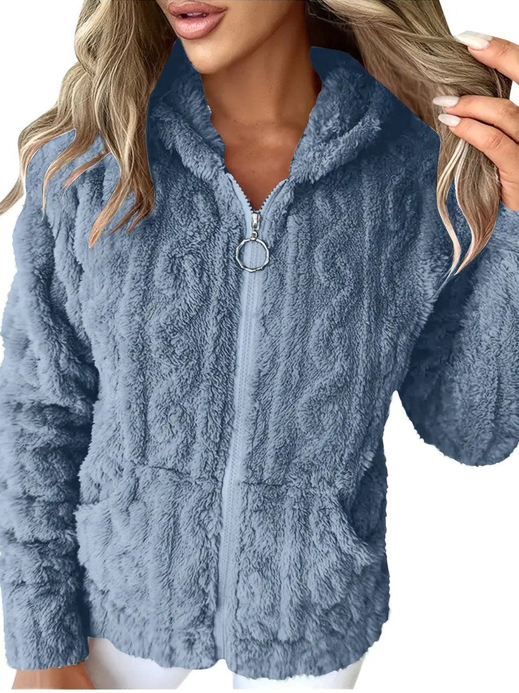 Vrouw draagt een lichtblauw teddyvest met ringtrekker en kabelpatroon, met een witte broek | Boutique Moda