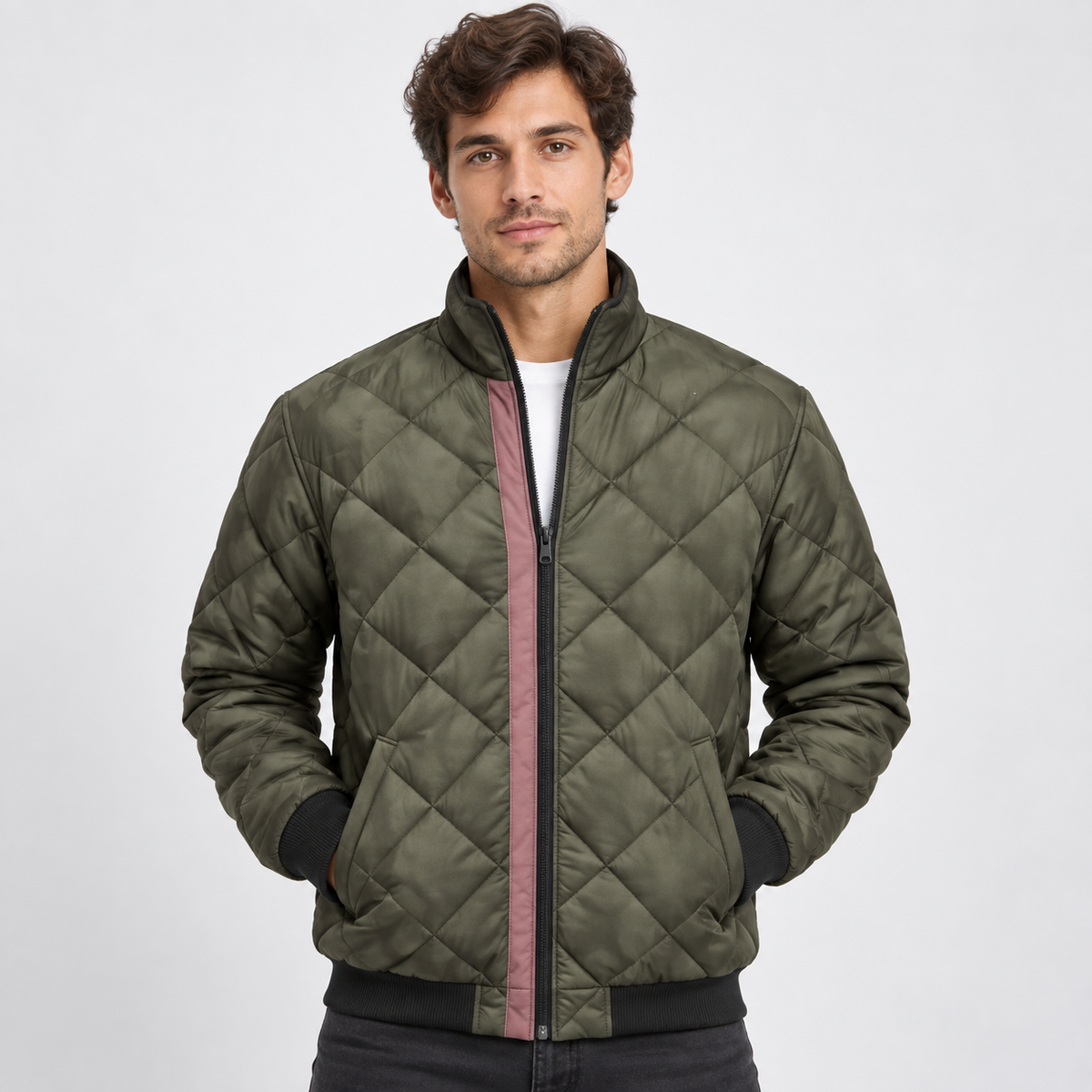 A man models an olive green diamond-quilted bomber jacket with a pink inner zip placket and ribbed black collar, cuffs and hem.