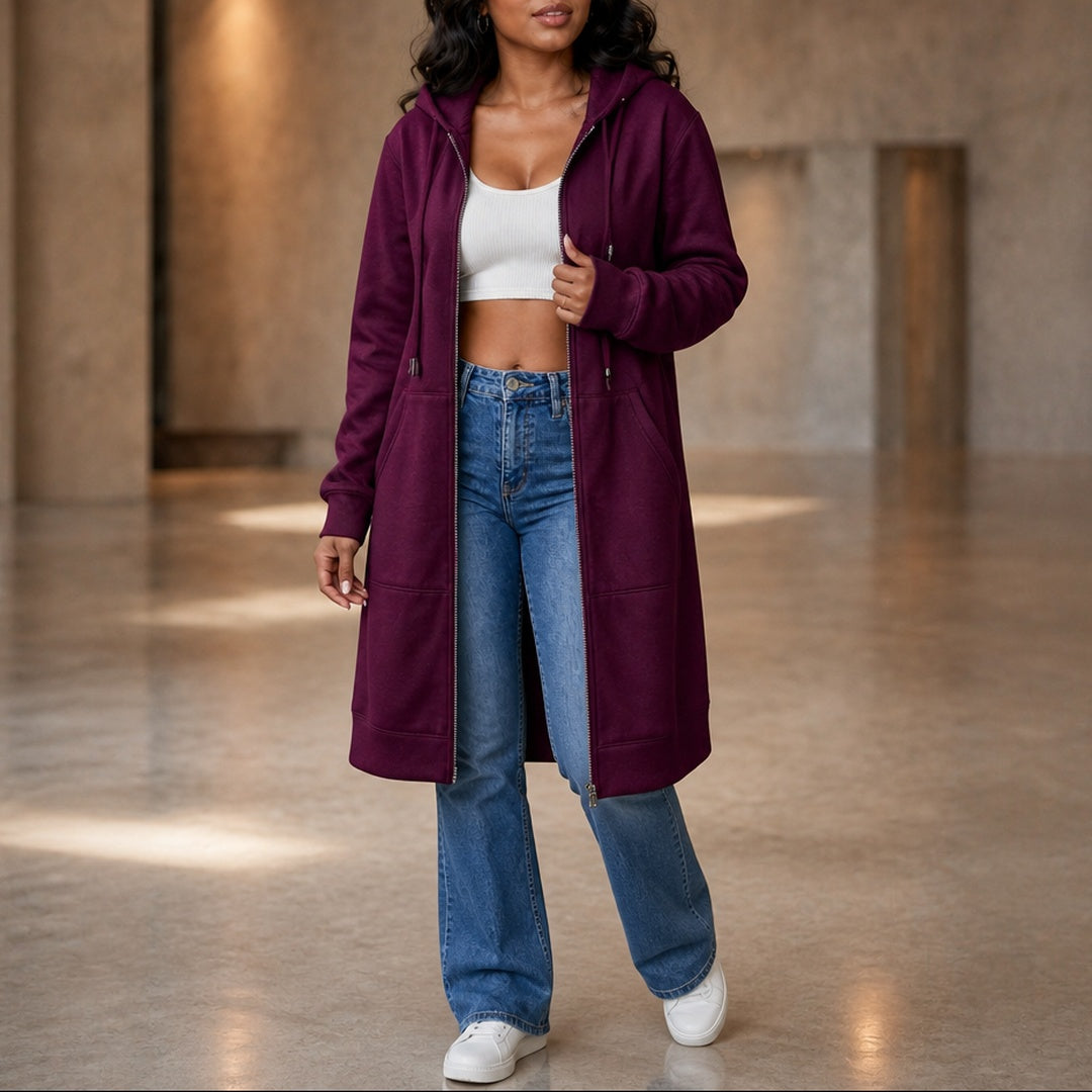Vrouw in een lang pruimkleurig vest met een jeans en witte sneakers | Boutique Moda