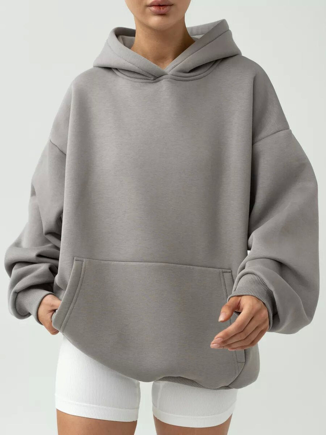 Vrouw in een grijze hoodie met brede zoomband, hand in de zak | Boutique Moda