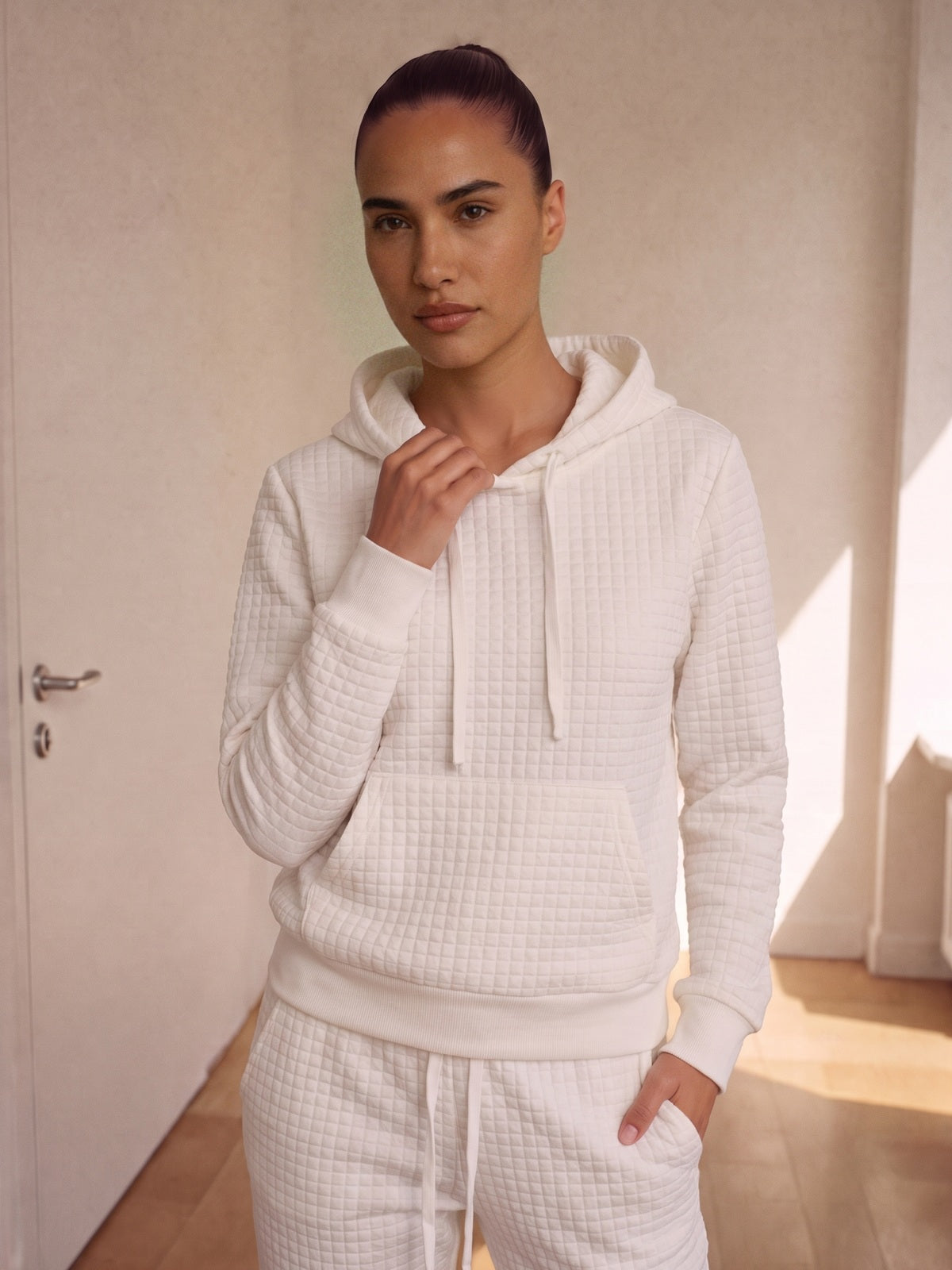Wit joggingpak met wafelstructuur, close-up van de hoodie aan een model
