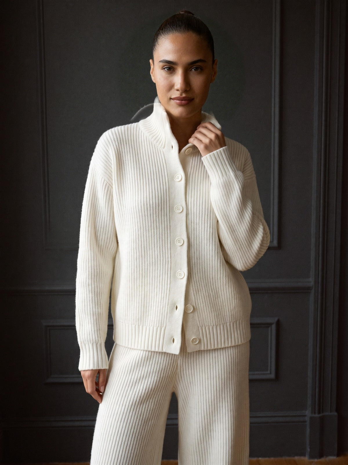 Witte co-ord set, close-up van het ribvest met hoge kraag aan een model