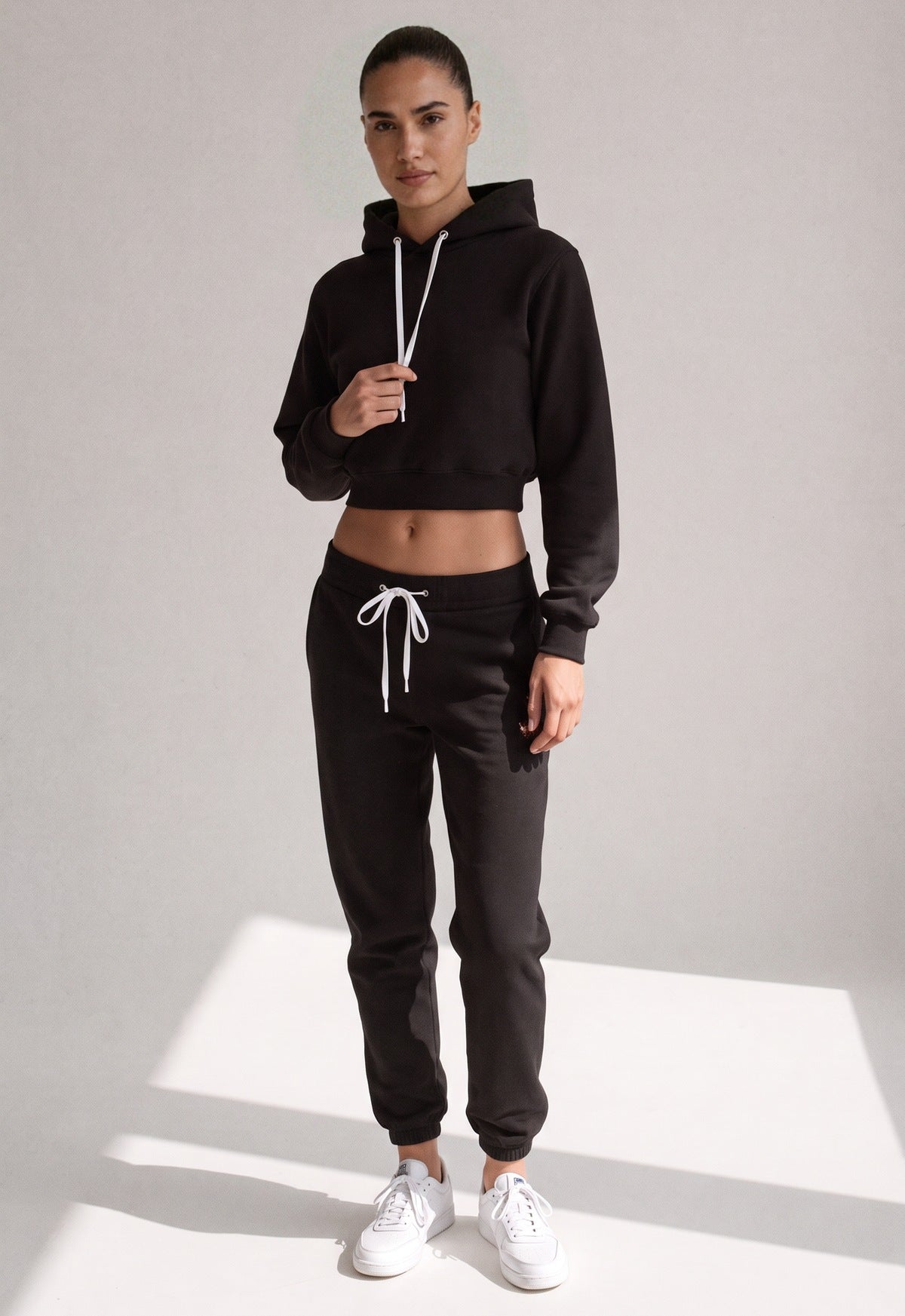 Joggingpak met korte hoodie in zwart aan een model, vooraanzicht