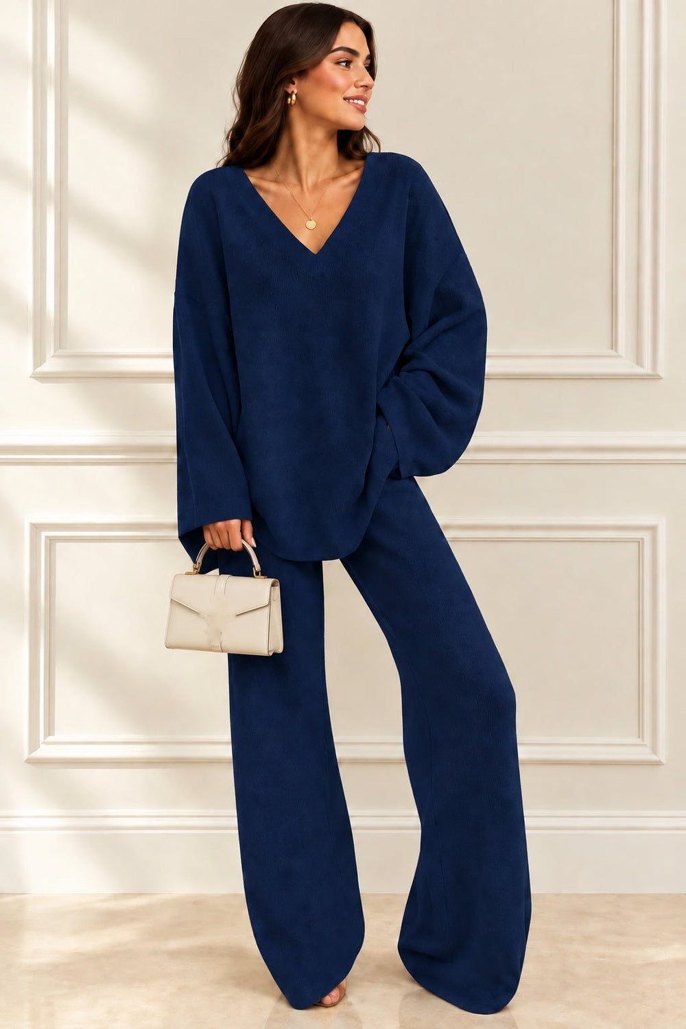 Gebreide co-ord set in marineblauw: losse trui met V-hals en wijde broek, ten voeten uit, licht gedraaid