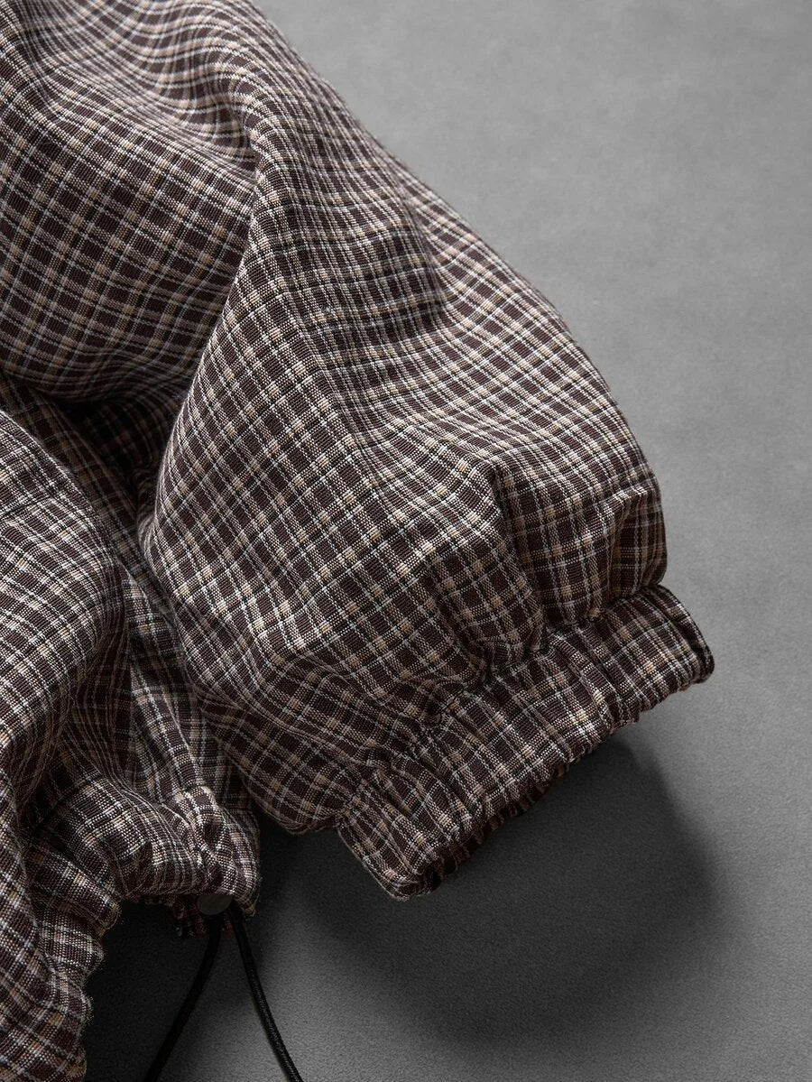Korte herenjas met capuchon in bruin geruit, close-up van de mouwboord