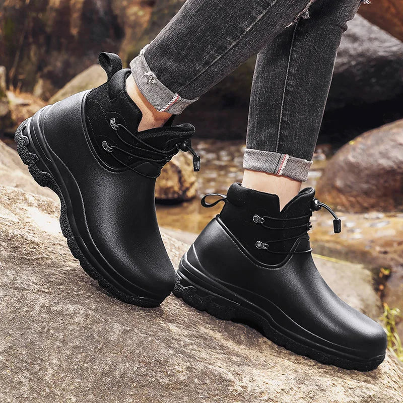 Zwarte regenlaarzen met ritssluiting, gedragen door persoon op rots | Boutique Moda