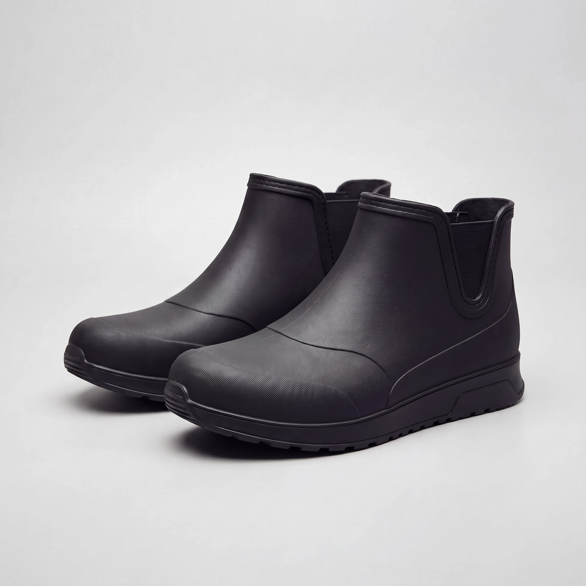 A pair of black rubber ankle boots with a chunky sole, photographed on a plain white background.