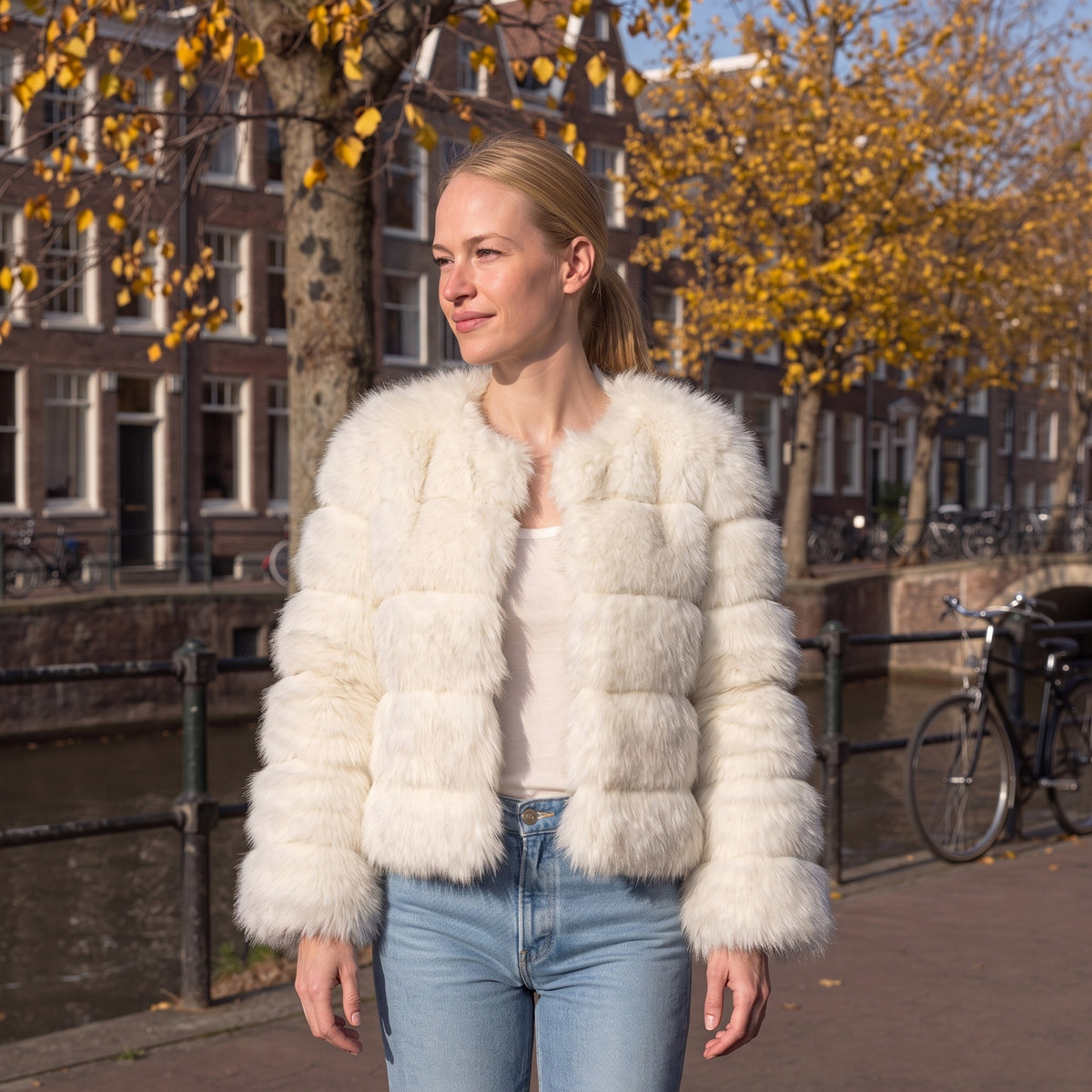 Vrouw draagt kort wit fluffy imitatiebont jasje bij gracht buiten | Boutique Moda