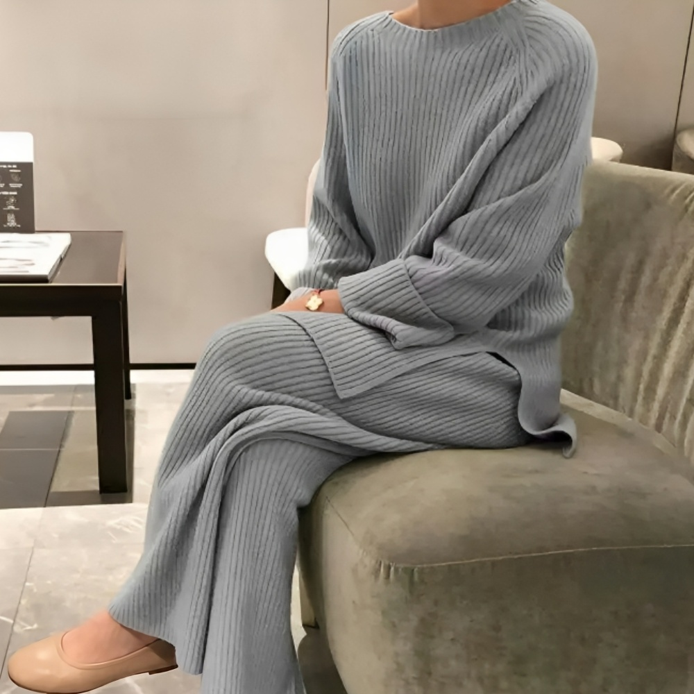 Grijze geribbelde loungeset met trui en broek, gedragen door zittende vrouw | Boutique Moda