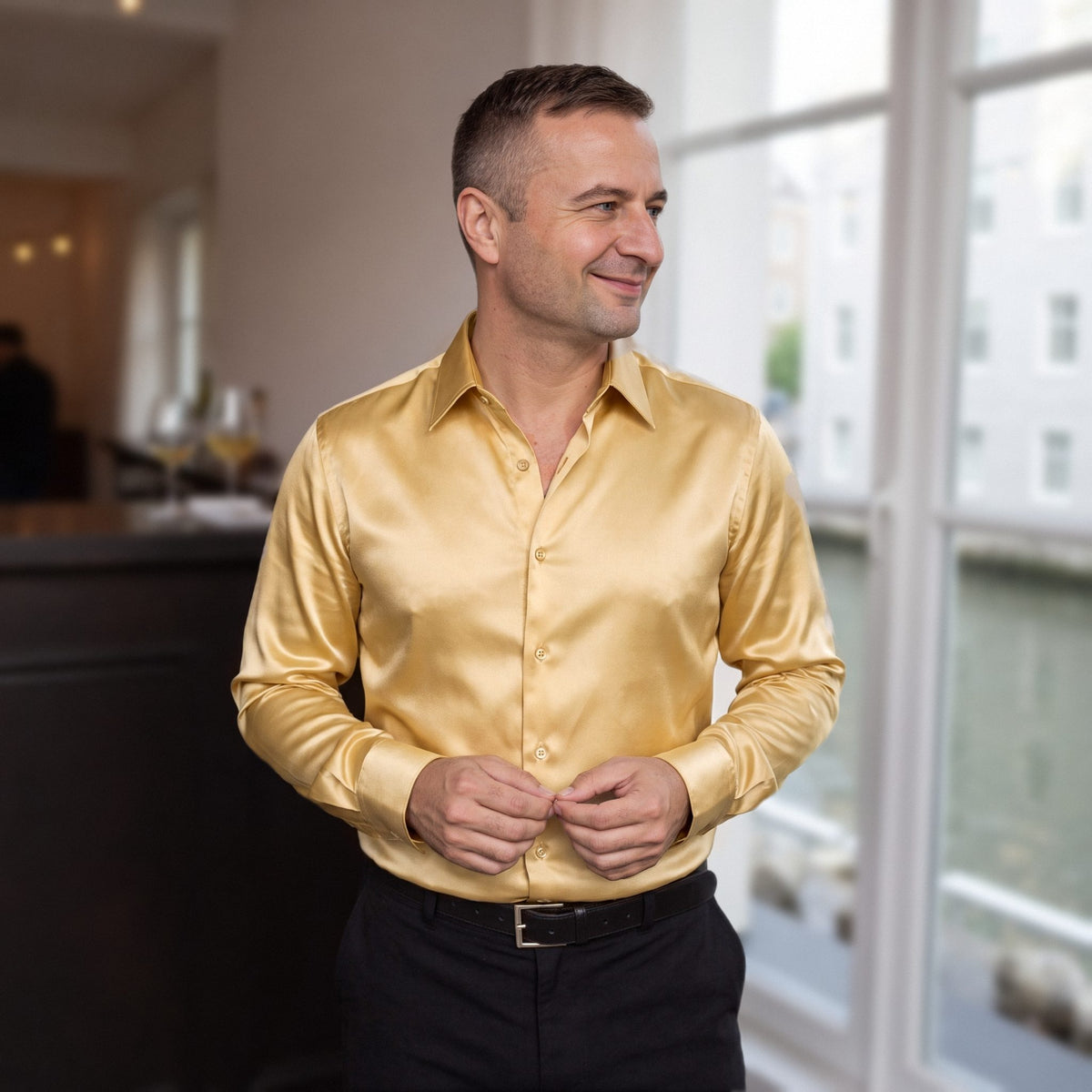 Man draagt goudkleurig glanzend overhemd in satijnlook, slim fit, in een café aan de gracht in Utrecht | Boutique Moda