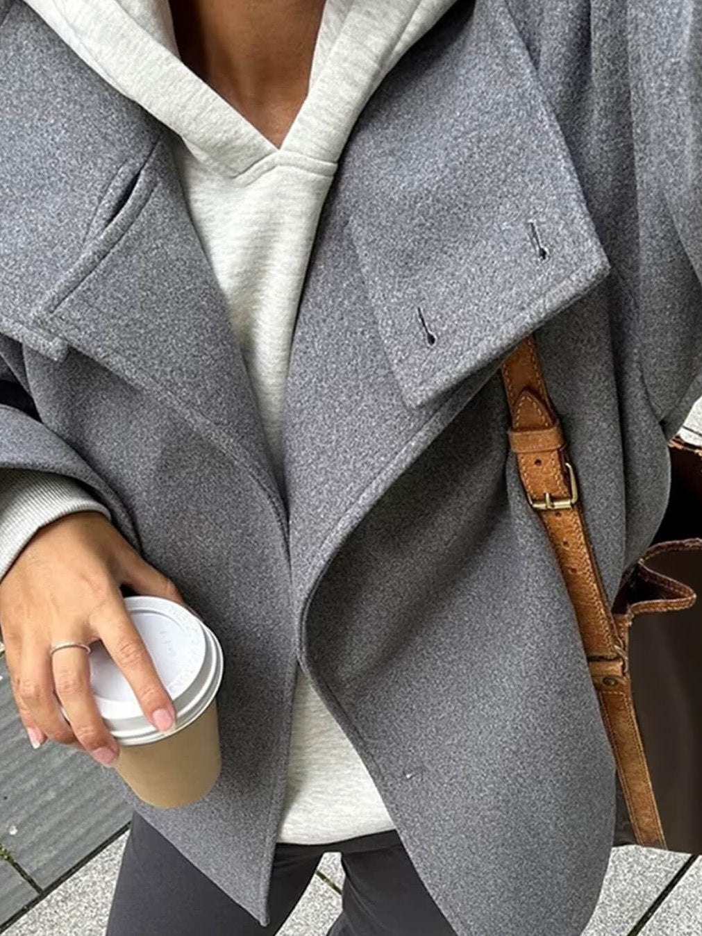 Grijze oversized jas met opstaande kraag, gedragen, met koffiebeker vastgehouden | Boutique Moda