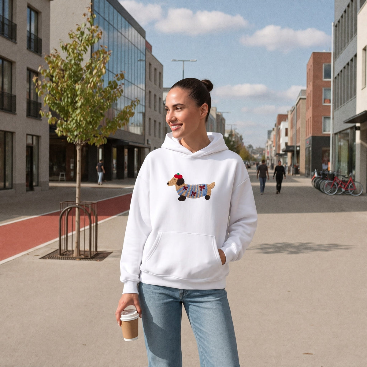 Witte hoodie met geborduurd hondje motief, gedragen door glimlachende vrouw buiten | Boutique Moda