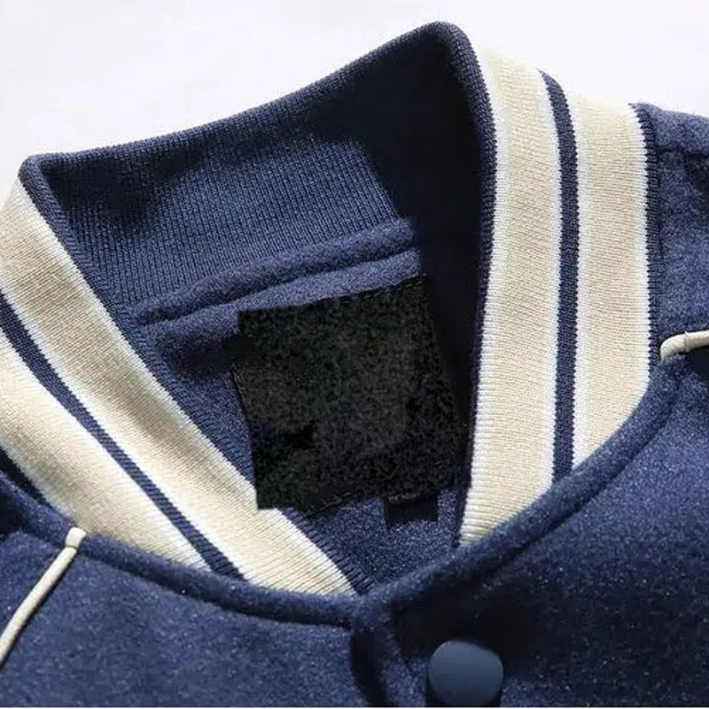 Detail van de gestreepte opstaande kraag en de drukknoop van de blauwe varsityjas | Boutique Moda